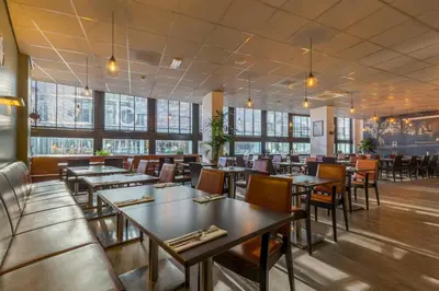 a restaurant with tables and chairs and windows at Leonardo Hotel Utrecht City Center in Utrecht