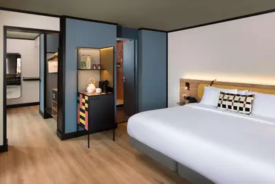 a bedroom with a large bed and a kitchen at Avani Museum Quarter Amsterdam Hotel in Amsterdam