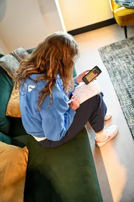 a young girl sitting on a couch reading a book at City Trip Hostels Amsterdam-Zaandam in Zaandam