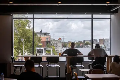 a group of people sitting at a bar with a large window at City Trip Hostels Amsterdam-Zaandam in Zaandam