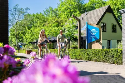 a man and woman riding bikes in front of a building at Résidence Lage Vuursche in Lage-Vuursche