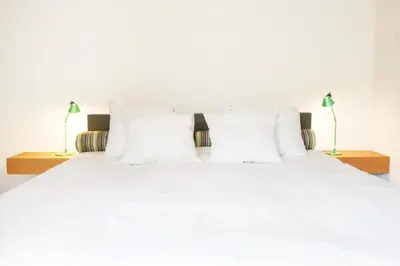 a white bed with white pillows and two lamps at blooming in Bergen