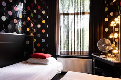 a bedroom with a bed and a window with a fan at Backstage Hotel Amsterdam in Amsterdam