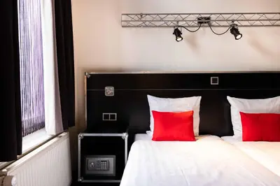 a bedroom with two beds with red pillows at Backstage Hotel Amsterdam in Amsterdam