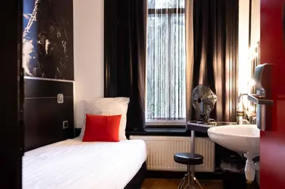 a bedroom with a bed with a red pillow and a sink at Backstage Hotel Amsterdam in Amsterdam