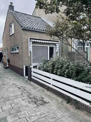 a house with a white fence in front of it at Tiny beachhouse - free parking in Noordwijk