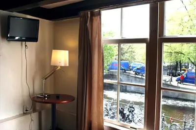a room with a window with a television and a table at Hostel The Veteran in Amsterdam