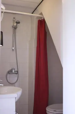 a bathroom with a shower with a red shower curtain at Hostel The Veteran in Amsterdam