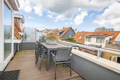 a balcony with a table and chairs on a balcony at Bodhi Beach House in Egmond aan Zee