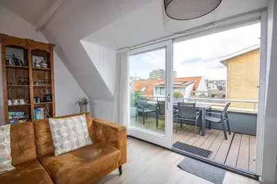 a living room with a couch and a sliding glass door at Bodhi Beach House in Egmond aan Zee