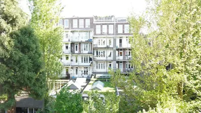 a tall white building in the middle of trees at Onefam Amstel in Amsterdam