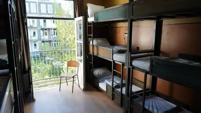 a room with bunk beds with a chair and a window at Onefam Amstel in Amsterdam