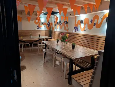 a row of tables in a restaurant with orange flags at Onefam Amstel in Amsterdam