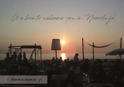 a group of people watching the sunset on a beach at Have a nice stay! - Beachhouse Zonneweelde in Noordwijk