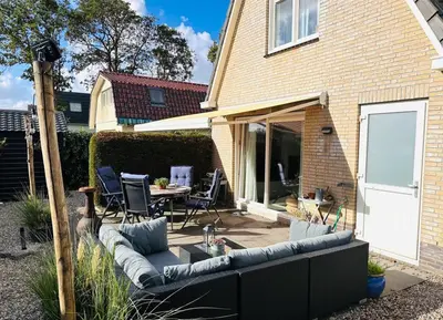 a patio with a couch and a table and chairs at Have a nice stay! - Beachhouse Zonneweelde in Noordwijk