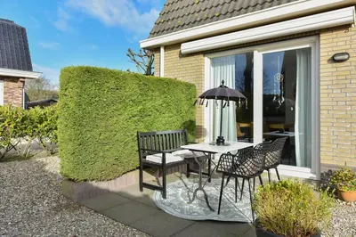 a patio with a table and chairs and an umbrella at Have a nice stay! - Beachhouse Zonneweelde in Noordwijk