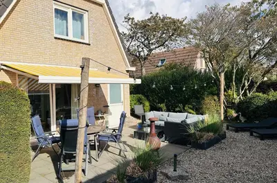 a backyard with a patio with a table and chairs at Have a nice stay! - Beachhouse Zonneweelde in Noordwijk