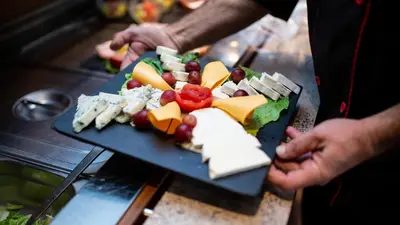 a person holding a plate of cheese and other foods at Royal Amsterdam Hotel in Amsterdam