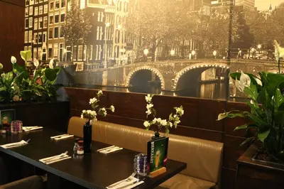 a table in a restaurant with a view of a bridge at Royal Amsterdam Hotel in Amsterdam