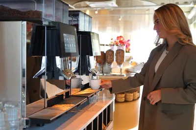 a woman standing in a bakery holding a cup of coffee at HOTEL ALKMAAR - Bar & Restaurant - Meeting & Events in Alkmaar