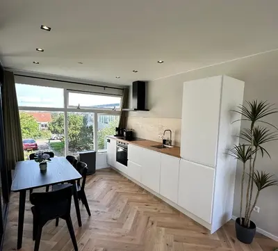 a kitchen with white cabinets and a table and a dining room at @92 in Zandvoort