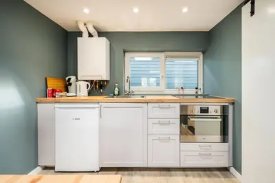a kitchen with white cabinets and a blue wall at Studio Luxe 31 Zandvoort met gratis parkeerplaats in Zandvoort