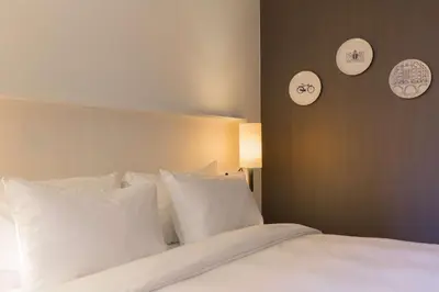 a bed with white pillows and clocks on the wall at Radisson Blu Hotel, Amsterdam City Center in Amsterdam