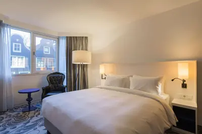 a bedroom with a large white bed and a chair at Radisson Blu Hotel, Amsterdam City Center in Amsterdam