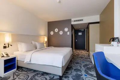 a bedroom with a large white bed and a blue chair at Radisson Blu Hotel, Amsterdam City Center in Amsterdam