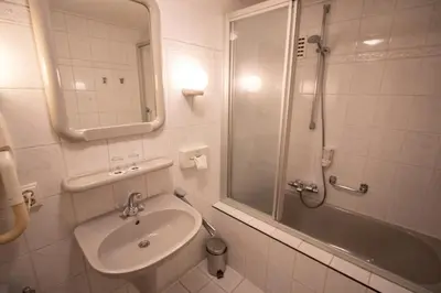 a white bathroom with a sink and a shower at Fletcher Hotel Restaurant Marijke in Bergen