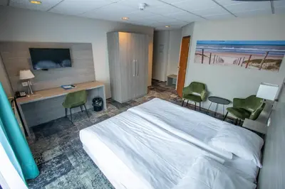a bedroom with a bed and a desk with two chairs at Fletcher Hotel Restaurant Marijke in Bergen