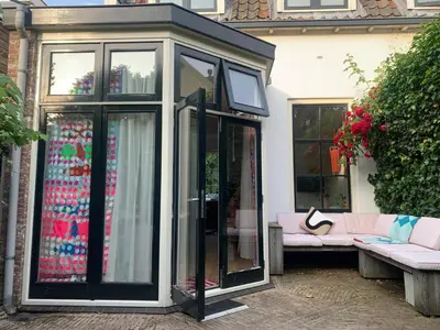 a glassconservatory with a pink couch in front of a house at The Great Hideaway in Vreeland