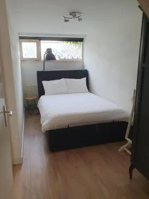 a bed in a small room with a window at 't Hoekhuisje in Katwijk aan Zee