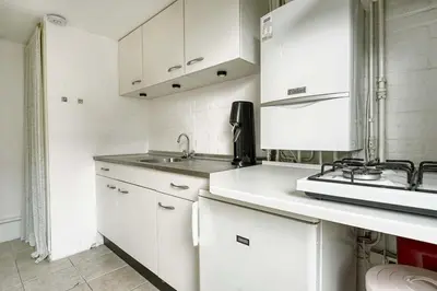 a white kitchen with white cabinets and a sink at 't Hoekhuisje in Katwijk aan Zee