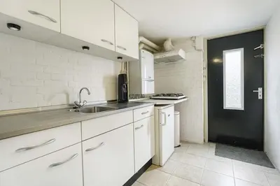 a kitchen with white cabinets and a sink at 't Hoekhuisje in Katwijk aan Zee