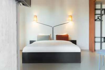 a bedroom with a bed with two lamps on it at Volkshotel in Amsterdam