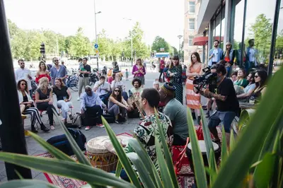 a crowd of people sitting on a sidewalk next to a street at Volkshotel in Amsterdam