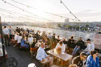 a crowd of people sitting at tables on a roof at Volkshotel in Amsterdam