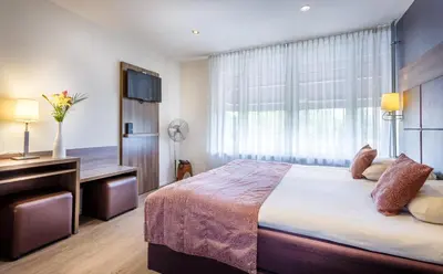 a bedroom with a bed and a desk and a window at Hotel Victorie in Amsterdam