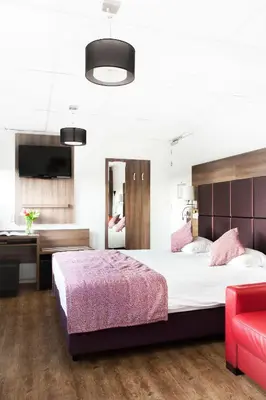 a bedroom with a large bed and a red chair at Hotel Victorie in Amsterdam