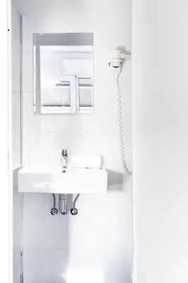 a white bathroom with a sink and a mirror at Hotel Victorie in Amsterdam