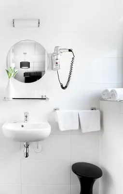 a white bathroom with a sink and a mirror at Hotel Victorie in Amsterdam