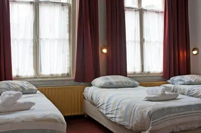 two beds in a room with windows at Hotel Torenzicht in Amsterdam