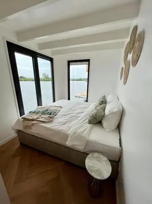 a bedroom with a large bed with two windows at Surla Houseboat 