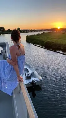 a woman standing on the edge of a boat on a river at Surla Houseboat 