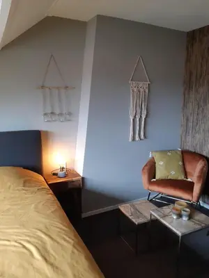 a bedroom with a bed and a chair and a table at Bed and Breakfast Kik en Bun in Katwijk aan Zee