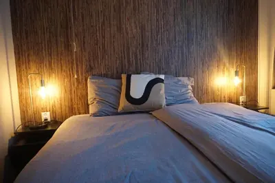 a bedroom with a large bed with two lights on it at Bed and Breakfast Kik en Bun in Katwijk aan Zee