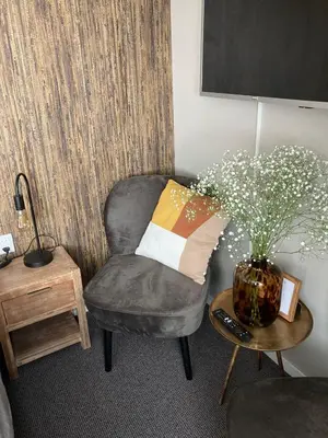 a living room with a chair and a vase with flowers at Bed and Breakfast Kik en Bun in Katwijk aan Zee