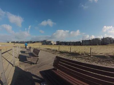 a row of benches on a boardwalk at the beach at Bed and Breakfast Kik en Bun in Katwijk aan Zee
