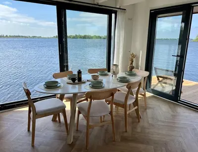 a dining room table with chairs and a view of the water at Surla houseboat 
